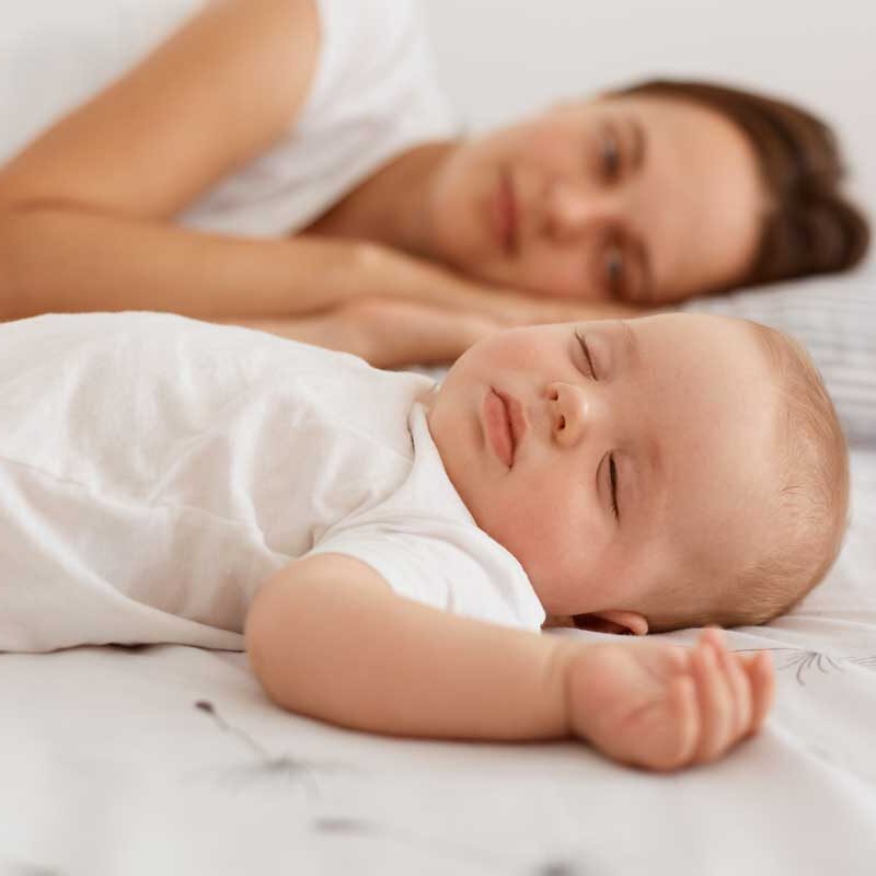 indoor-shot-attractive-dark-haired-female-wearing-white-t-shirt-lying-bed-with-her-infant-baby-having-rest-together-mommy-looking-her-cute-daughter